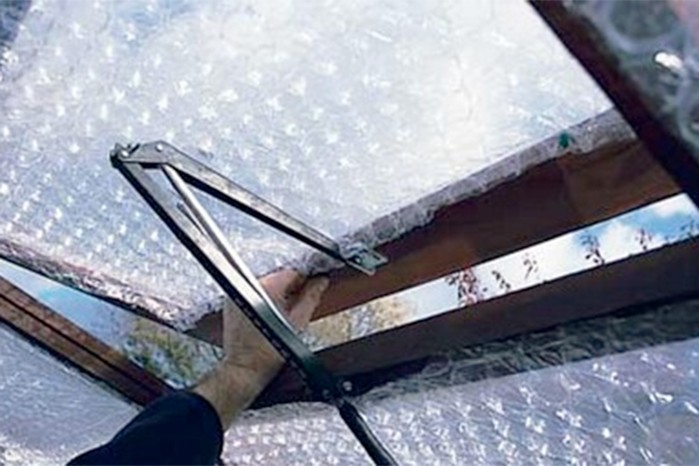 Fitting panels of bubble-wrap into panes of a greenhouse Fitting panels of bubble-wrap into panes of a greenhouse